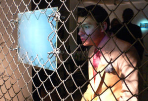 Person looking at hologram by Martina Mrongovius attached to fence